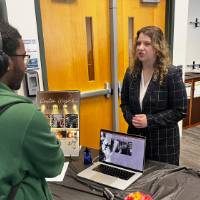 Event attendee talking with student at their booth